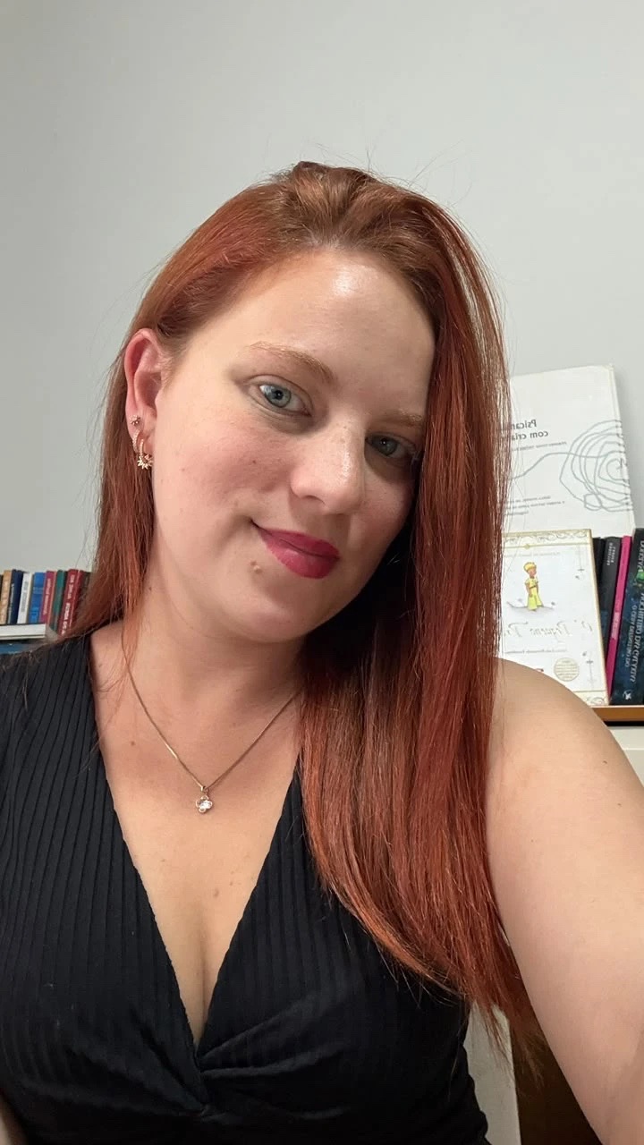 Bianca Boregio em seu espaço de trabalho, com livros de psicanálise ao fundo